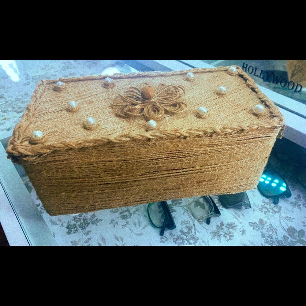 The storage bin is a tan color with pearls and a flower.